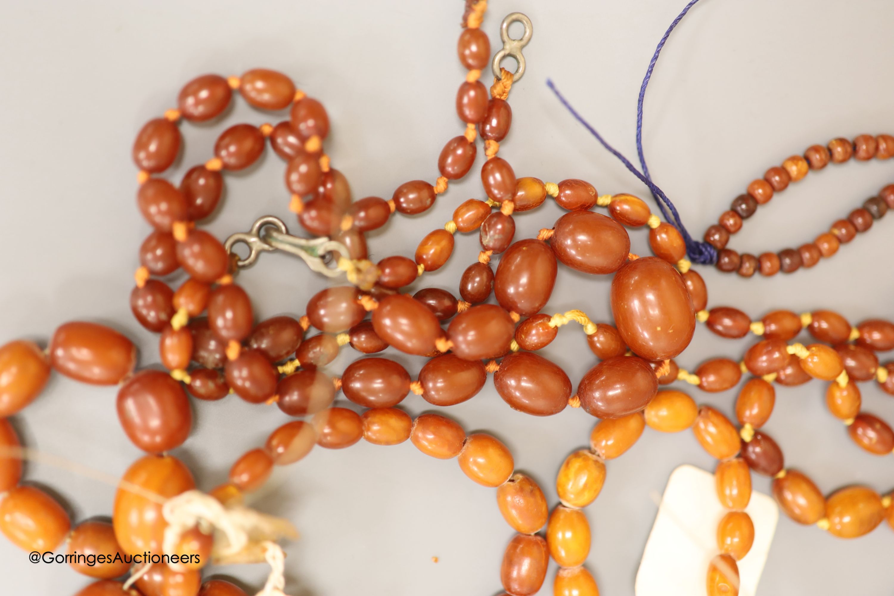 Nine assorted single strand amber bead necklaces, longest approximately 46cm, gross weight 173 grams and one simulated amber bead necklace.